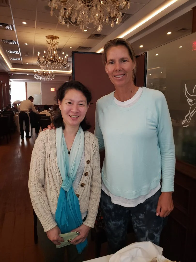 A guest photographed with a former top professional tennis player in a chandelier-lit private dining room