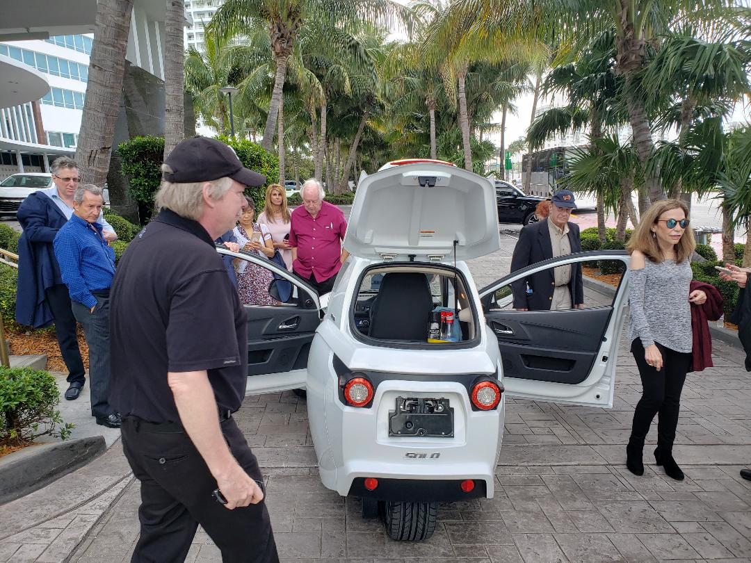 Investors inspecting the cargo compartment of an electric vehicle demonstration model
