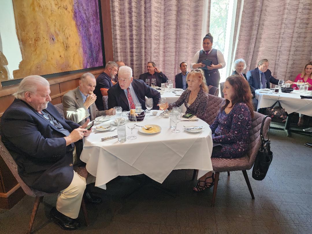 Guests conversing over lunch at a round table in a sunlit private dining room