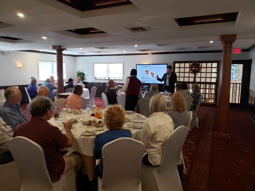 A presenter discussing a medical device slide with guests over dinner