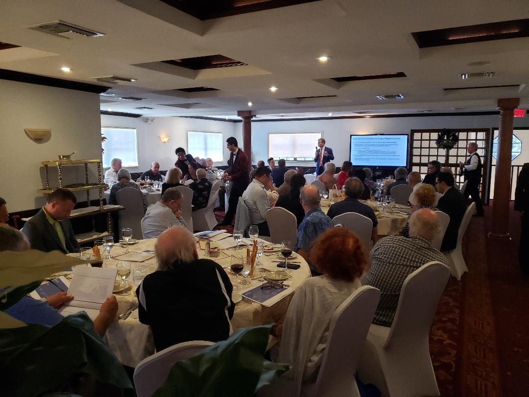 A full banquet room of investors listening to a management presentation