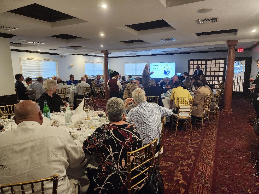 A large audience at round tables watching a company presentation