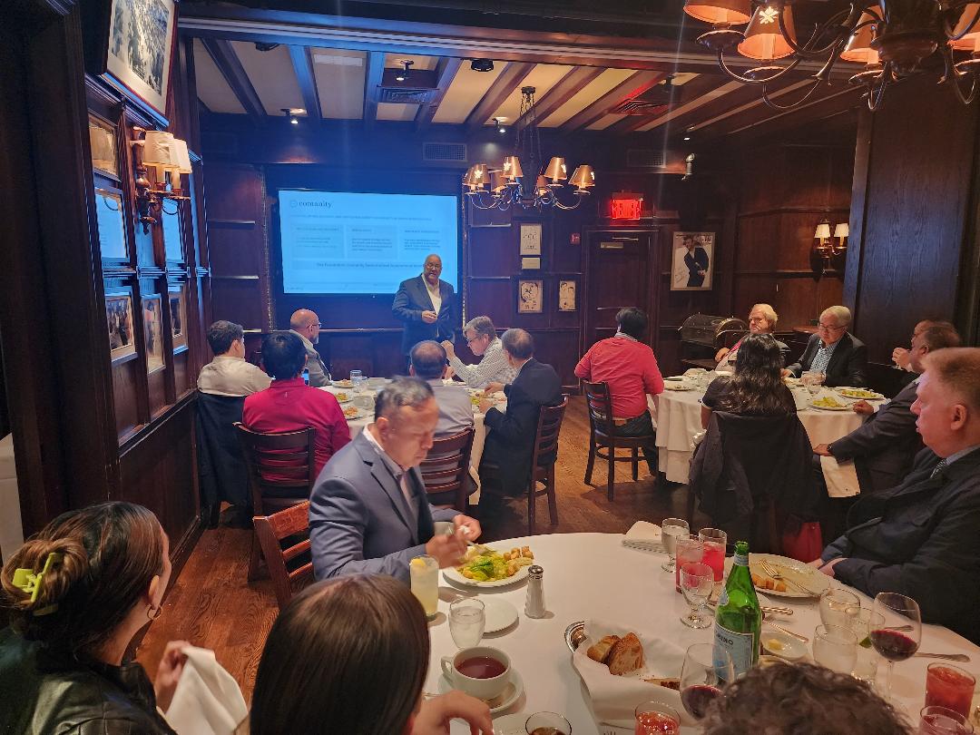 A presenter addressing investors over dinner in a wood-paneled private dining room