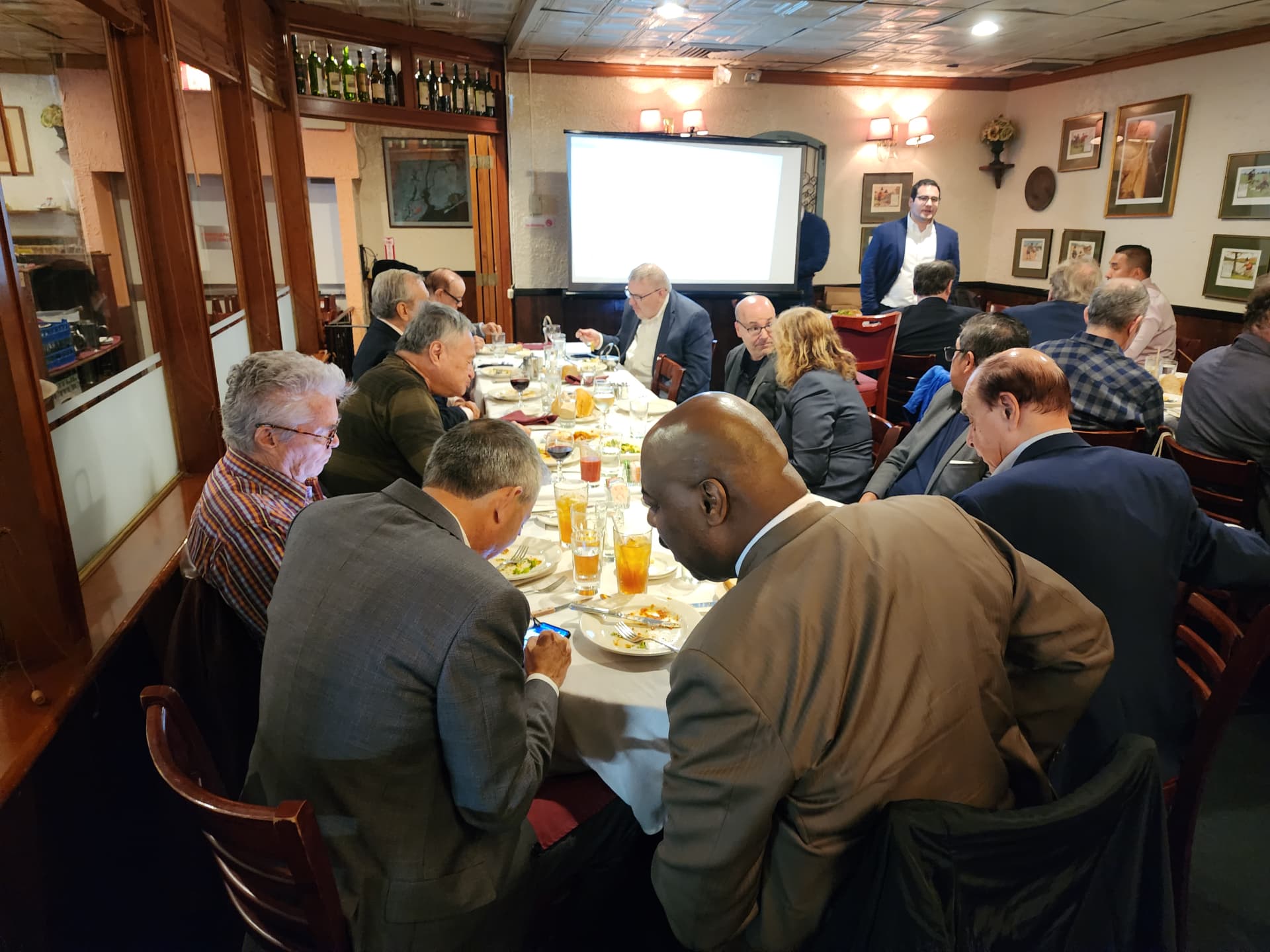 Attendees dining at a long table facing the presentation screen