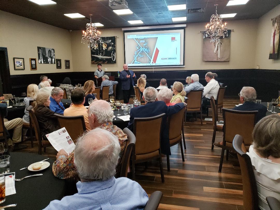 An executive presenting a brand strategy slide to seated investors at dinner
