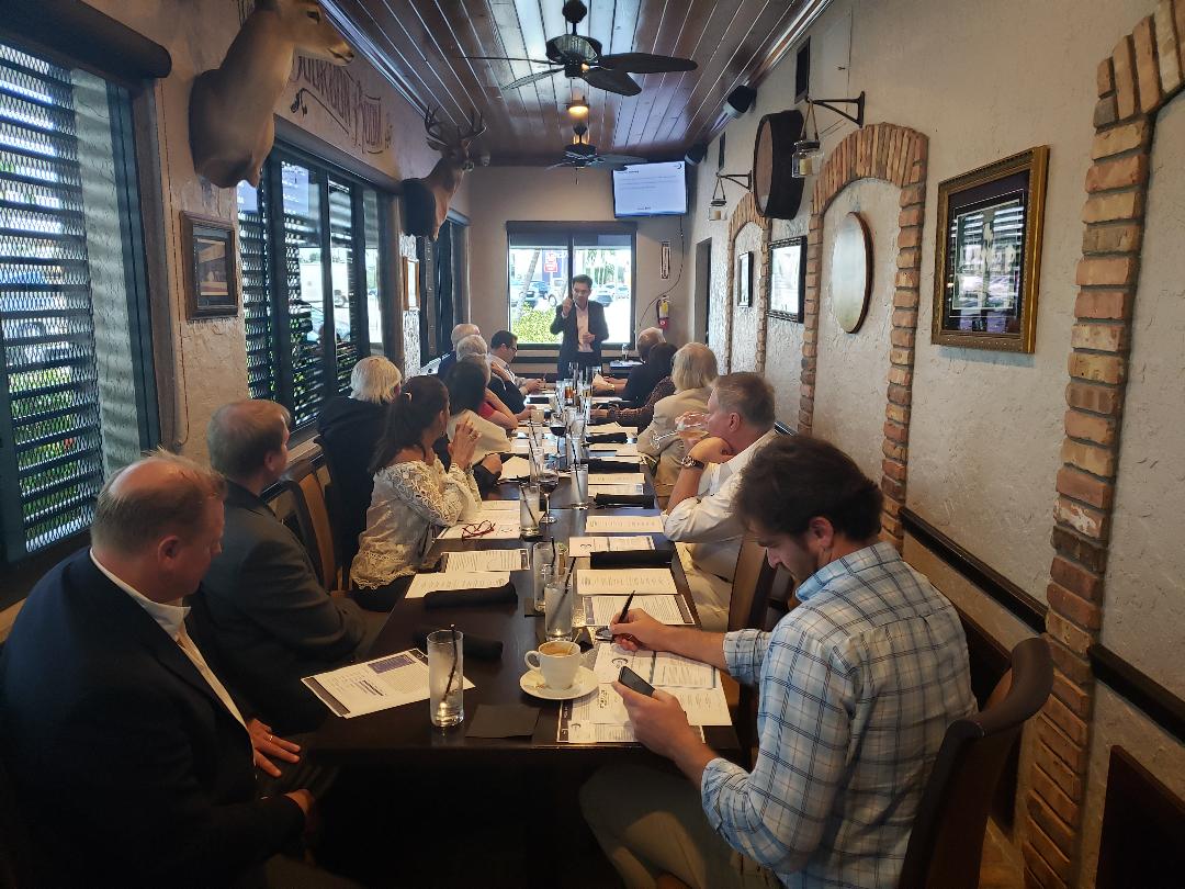 Guests reviewing handouts as a presenter speaks at the head of the table