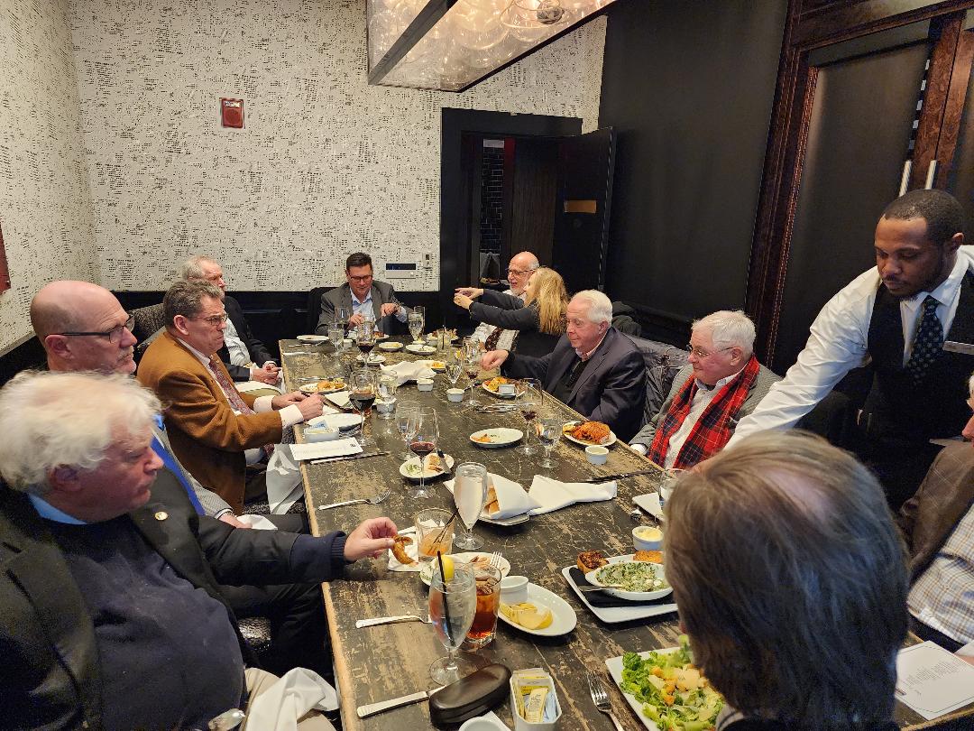 Investors seated at a rustic wooden table as servers bring the main course