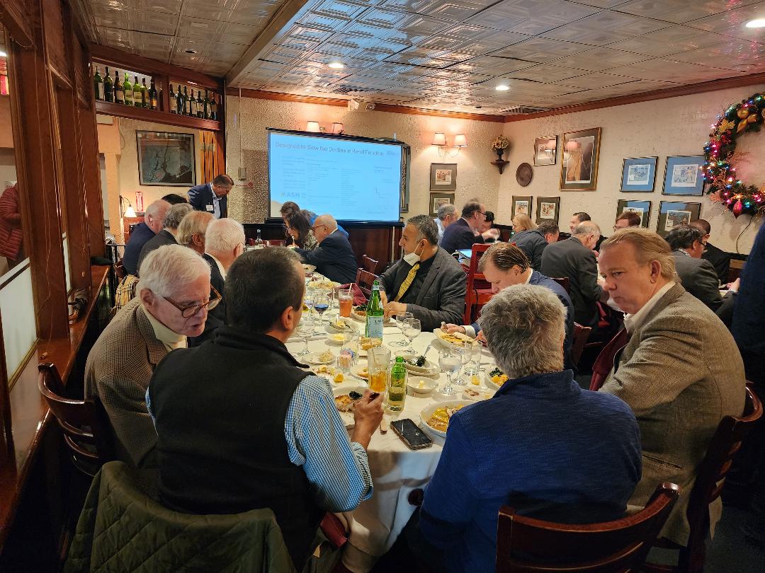 Attendees dining while a clinical results slide is presented on screen