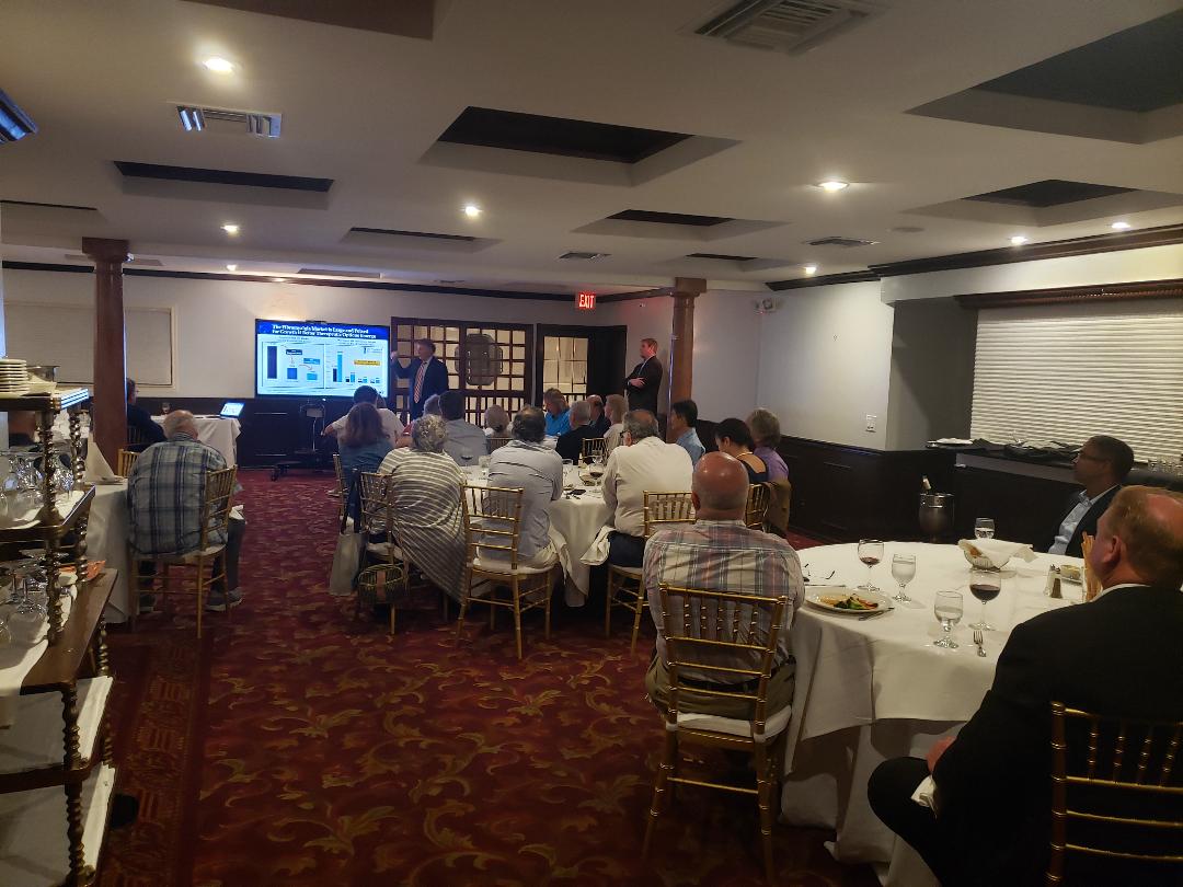 Two presenters reviewing market slides for a seated banquet audience