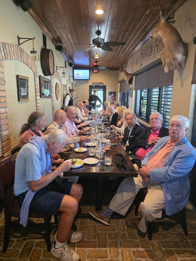 A long communal table of guests at a rustic private dining room