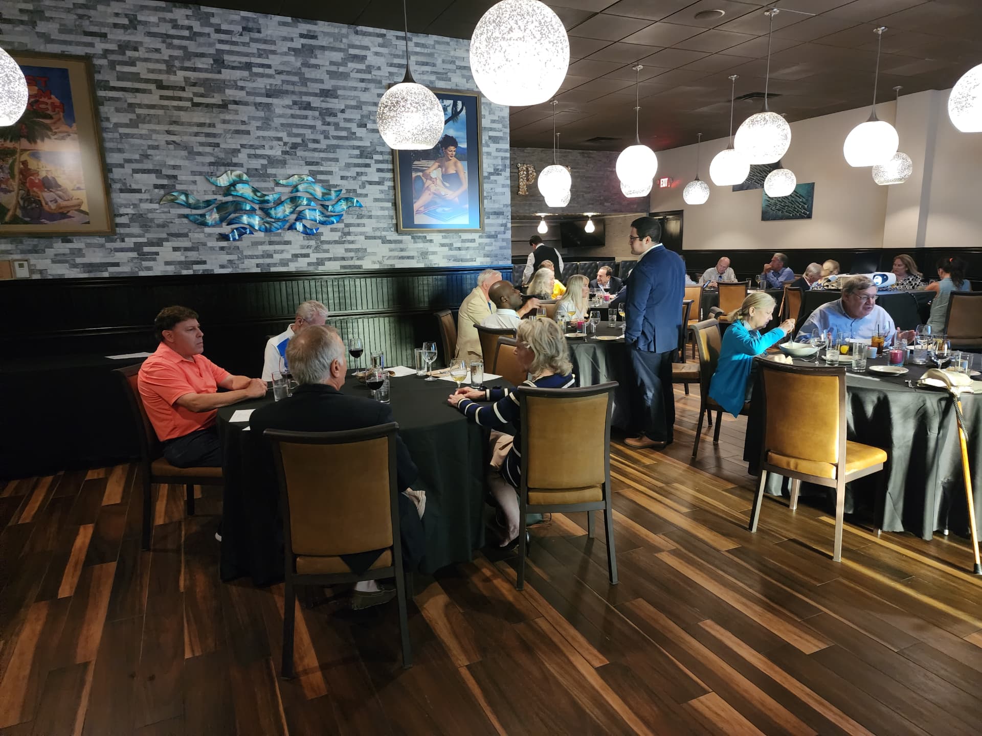 Guests seated at black-linen tables in a bright contemporary restaurant meeting
