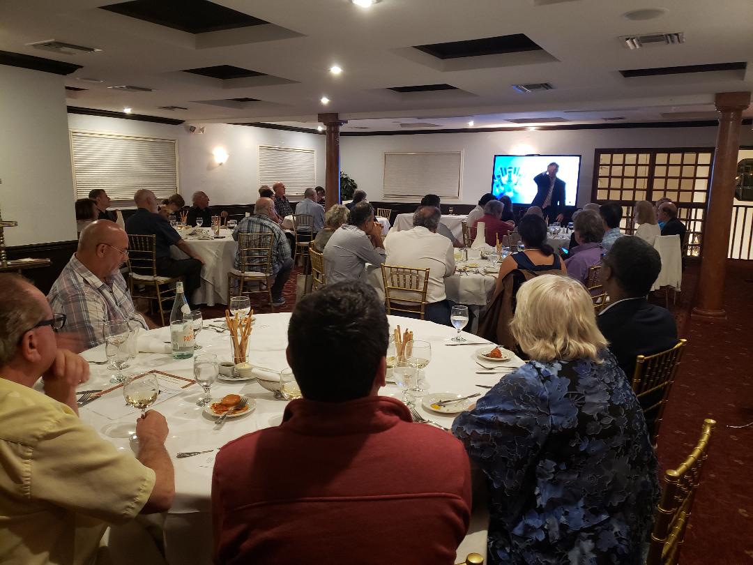 A large banquet room of guests watching a video presentation