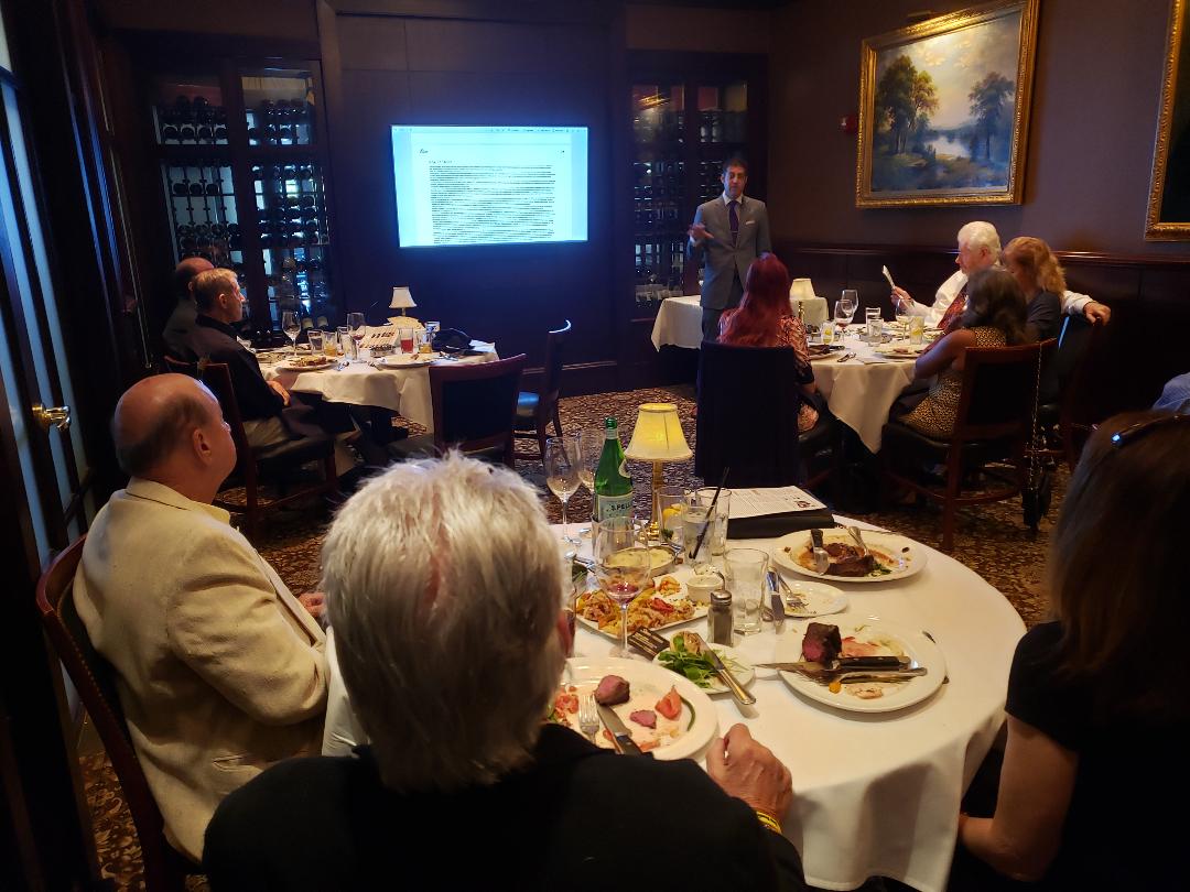 Guests dining while a presenter reviews slides in a private room