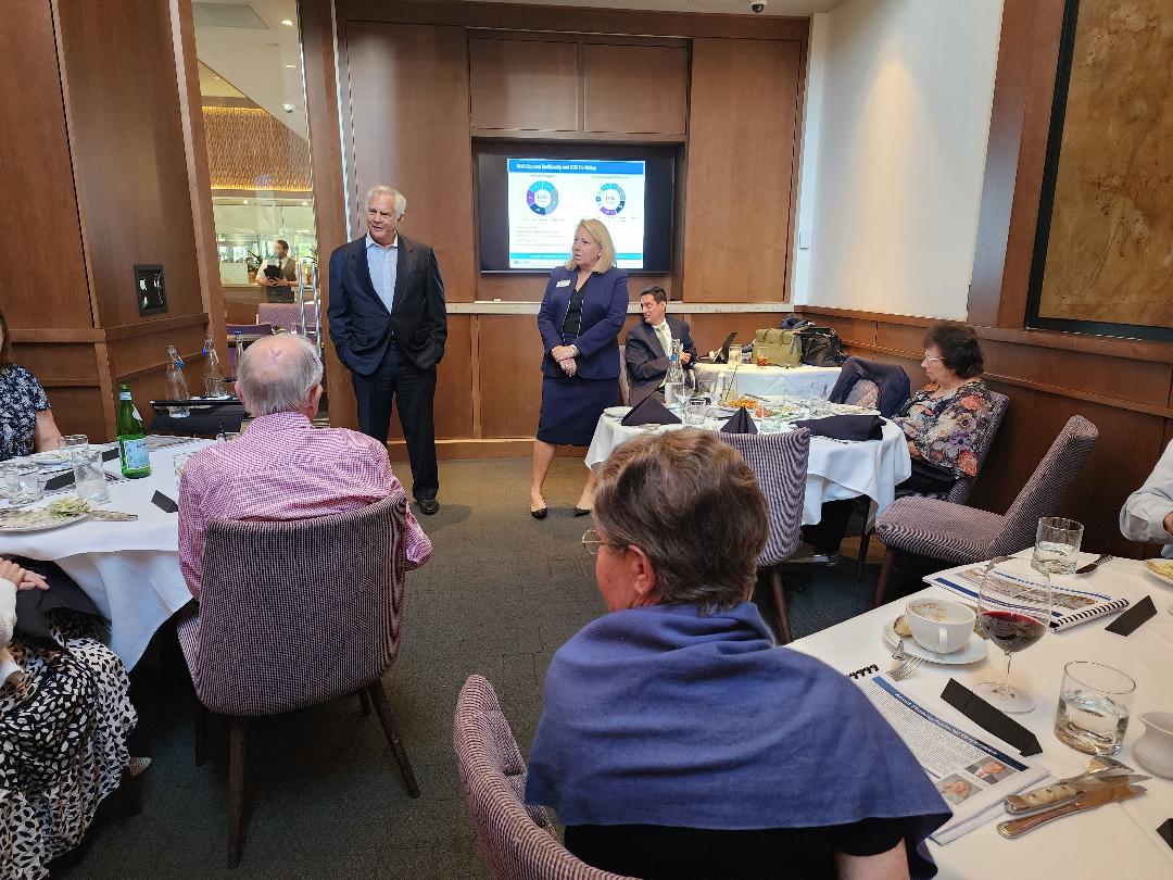 Executives presenting a portfolio slide to guests at a luncheon meeting