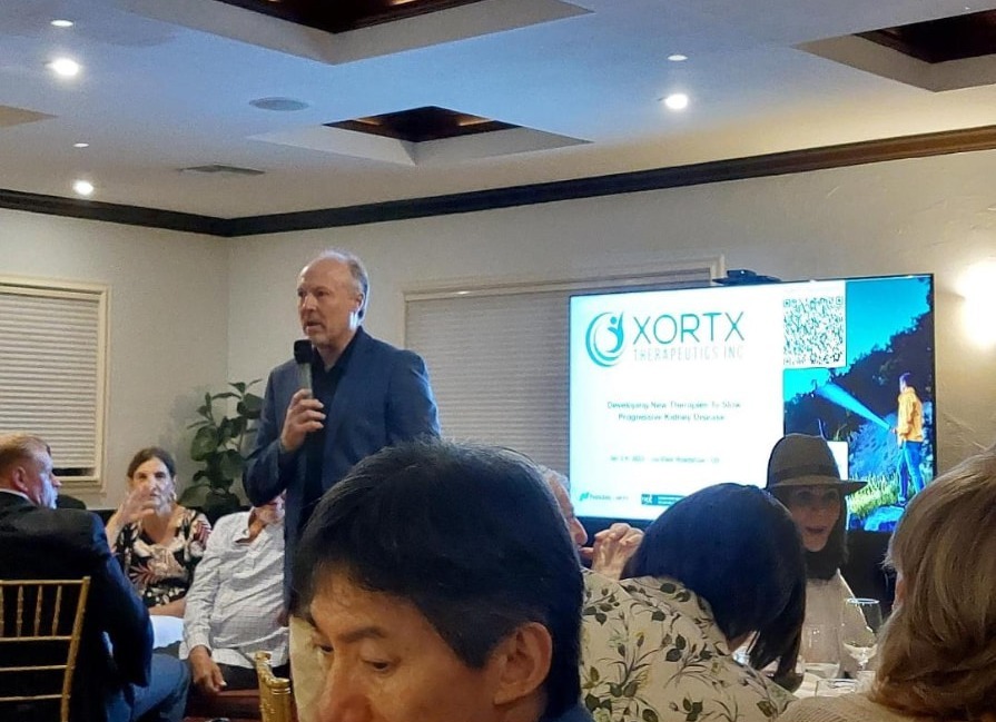 A host with a microphone introducing a company to guests seated in a private dining room