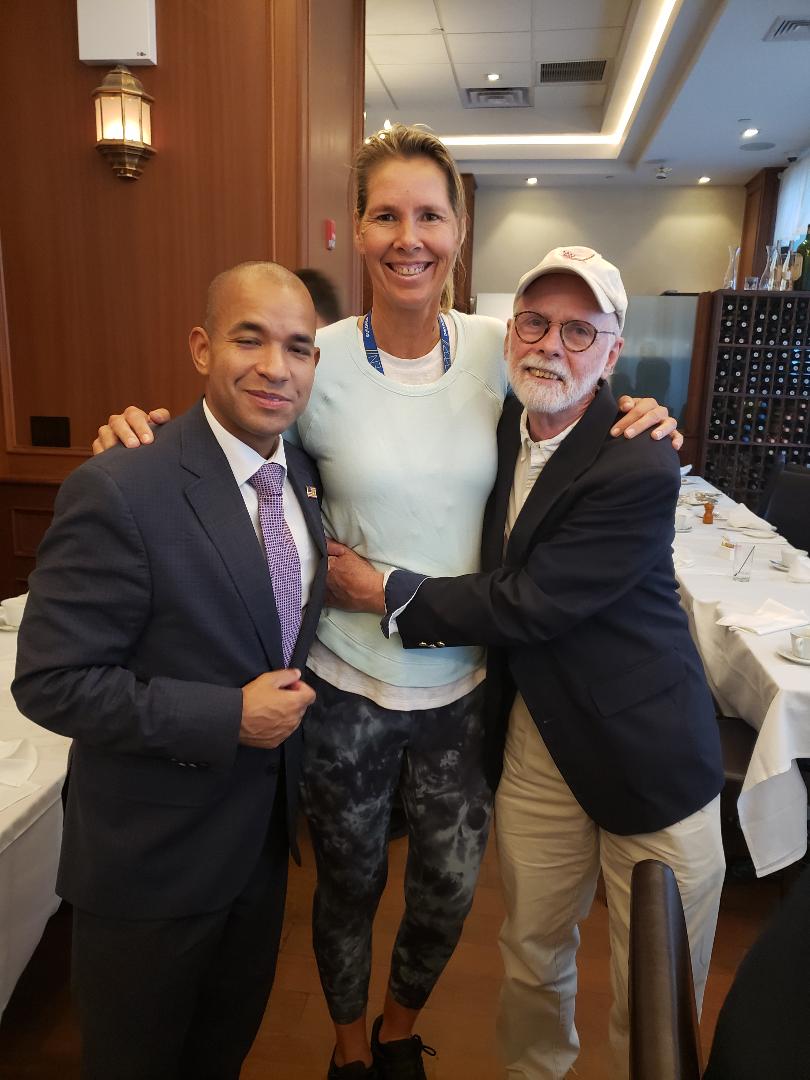 Two attendees posing with a former professional tennis player before dinner