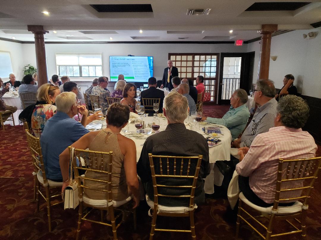 A presenter addressing a full banquet room of guests at round tables