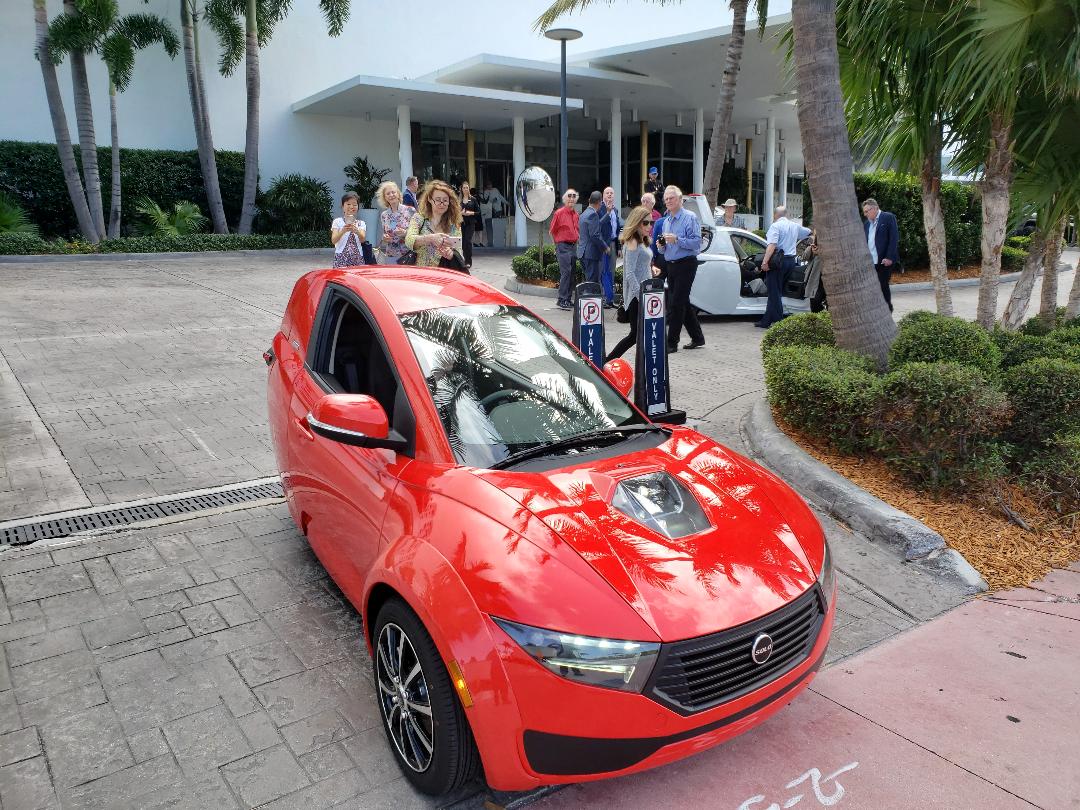 A red three-wheeled electric vehicle on display for investors at a hotel entrance